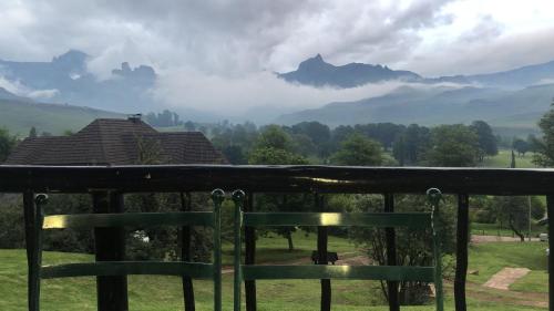 a bench on a balcony with mountains in the background at Fairways Holiday Accommodation in Drakensberg Garden
