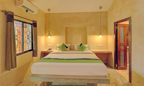 a bedroom with a large bed and a window at Treebo Morjim Banyan Resort in Morjim