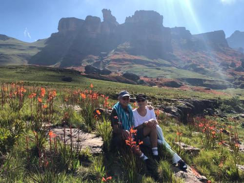 a man and woman sitting on a rock in a field of flowers at Fairways Holiday Accommodation in Drakensberg Garden
