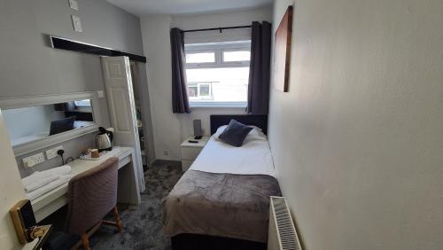a small room with a bed and a desk and a window at Y Gwynedd Inn in Llanberis