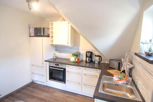 a kitchen with white cabinets and a sink at Ferienwohnung Ankerlicht2 in Westerland