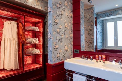 a bathroom with two sinks and a red wall at Q92 Noto Hotel in Noto