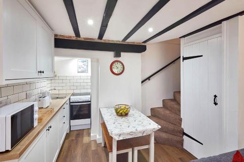 a kitchen with white cabinets and a table with a bowl on it at Host & Stay - Thimble Cottage in Whitby