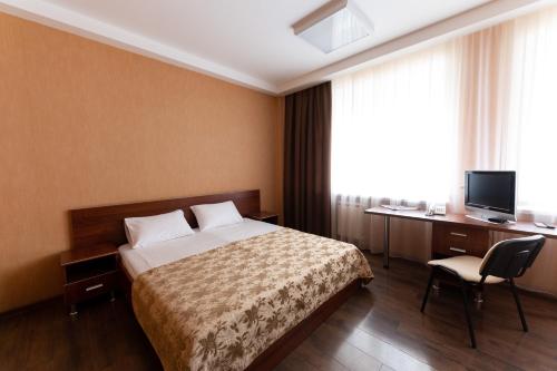 a hotel room with a bed and a desk and a television at Hotel Yaik in Orenburg