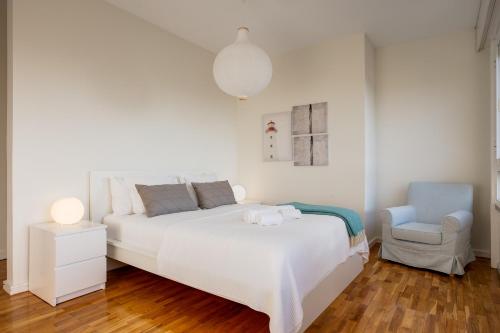 a white bedroom with a bed and a chair at Amazing Tailor Made Penthouse by the Beach #1 in Oeiras