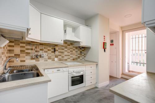 a kitchen with white cabinets and a sink at Amazing Tailor Made Penthouse by the Beach #1 in Oeiras