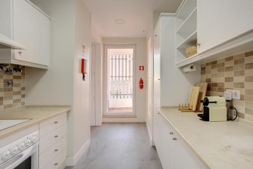 a kitchen with white counters and a window at Amazing Tailor Made Penthouse by the Beach #1 in Oeiras