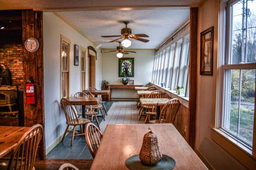 um restaurante com mesas e cadeiras de madeira e janelas em Brook Road Inn em Goshen