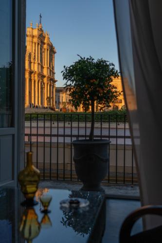 a vase with a tree in front of a building at Q92 Noto in Noto