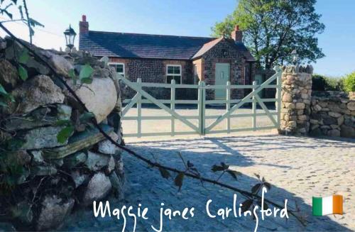 a fence in front of a house with a gate at Maggie janes cottage Carlingford omealth in Ó Méith