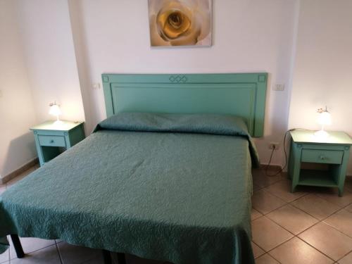 a bedroom with a green bed with two night stands at Il Roseto in Procchio