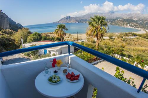 a table on a balcony with a view of the ocean at Plakias Bay Hotel in Plakias
