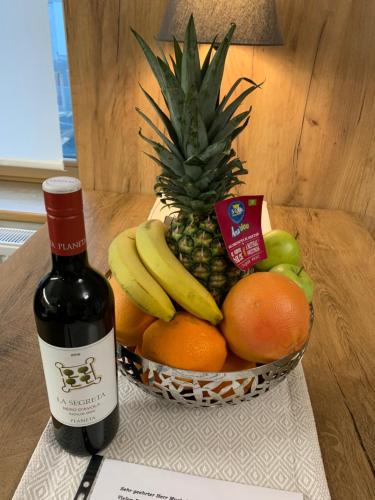 a bottle of wine next to a basket of fruit at Apartmany Rezidence Klostermann & Javor & Skalka in Železná Ruda