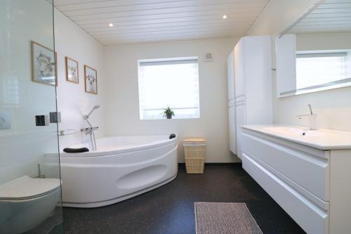 a white bathroom with a tub and a toilet at Stykkjastova - view and positioning in Kvívík