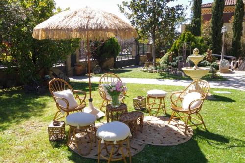 a group of chairs and tables under a straw umbrella at Hotel El Juglar in Olite