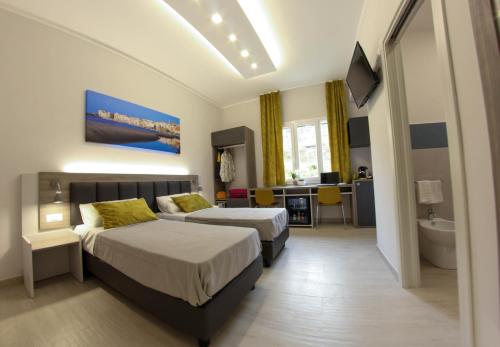 a hotel room with two beds and a bathroom at YEASY smart rooms Cefalù in Cefalù