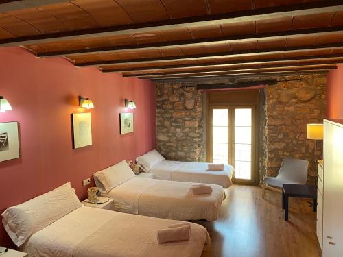 a room with four beds in a room with a stone wall at La Polaina in Montblanc