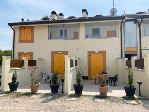 a house with yellow doors and potted plants at Gold Oasi - Business Solution in Ferrara