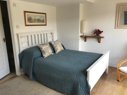 a bedroom with a bed with a blue comforter at Garden Studio in Marlow