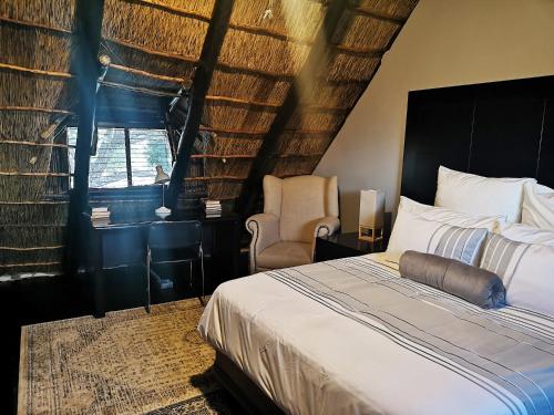 a bedroom with a bed and a chair and a window at Sasavona Game Lodge in Warmbaths