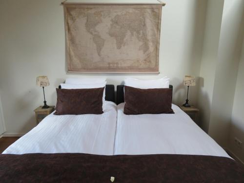a bedroom with a bed with white sheets and brown pillows at B&B De Willemshoeve in Wageningen