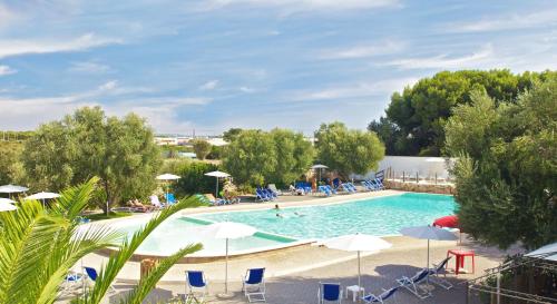 a large swimming pool with chairs and umbrellas at Happy Camp mobile homes in Porto Cesareo Camping in Porto Cesareo