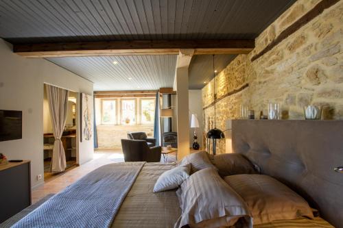 a large bed in a room with a stone wall at Le Clos de la Tour in Sainte-Nathalène