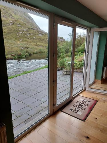 a room with sliding glass doors with a view of a river at Delphi Lodge in Leenaun
