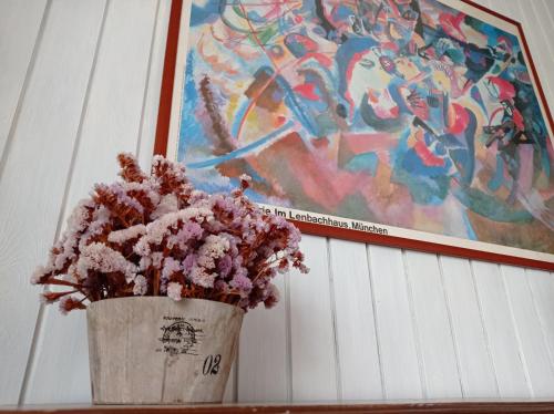 a vase with flowers in it next to a painting at Gli Archi Country Home in Giurdignano