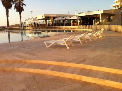 a row of white benches sitting next to a pool at Jardin del Mar Costanera in Coquimbo