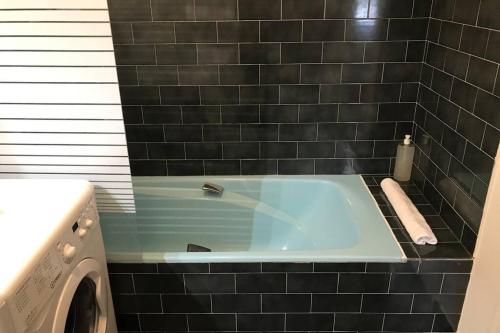 La salle de bains est pourvue d'une baignoire et de carrelage noir. dans l'établissement CHEZ JACQUES - terrasse avec vue lac et montagne, à Annecy