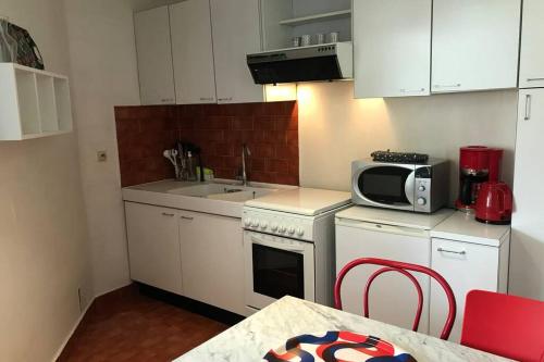 - une cuisine avec des placards blancs, un four micro-ondes et une table dans l'établissement CHEZ JACQUES - terrasse avec vue lac et montagne, à Annecy