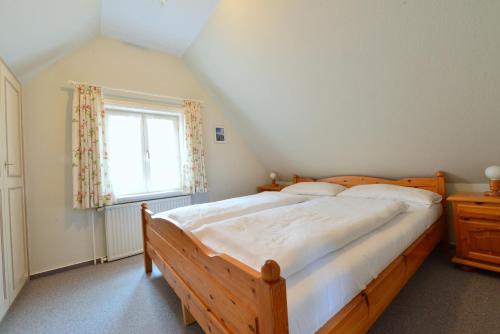 ein Schlafzimmer mit einem Holzbett und einem Fenster in der Unterkunft Amrum in Wyk auf Föhr