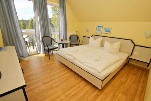 een slaapkamer met een wit bed en een balkon bij F-1010 Strandhaus Mönchgut B&B Doppelzimmer Nr 35 in Lobbe