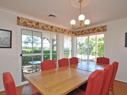a dining room with a wooden table and red chairs at Beggars Bridge Vineyard Homestead with pool and tennis in Rothbury