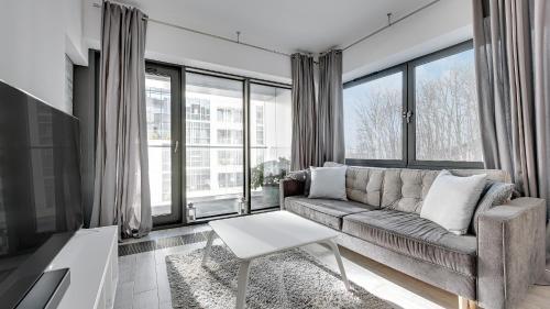 a living room with a couch and large windows at Dom & House - Apartments Baltiq Plaza in Gdynia