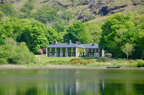 a large house sitting on the side of a lake at Delphi Lodge in Leenaun