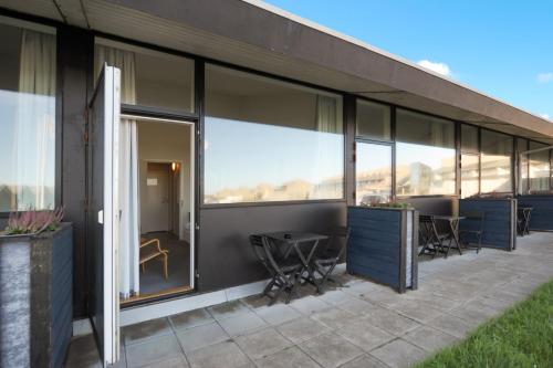 a building with large windows and tables and chairs at Landal Hotel Fyrklit in Hirtshals