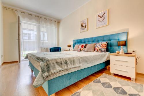 een slaapkamer met een blauw bed en een raam bij Apartament MORSKI ZAKĄTEK in Pobierowo