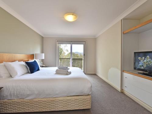 um quarto com uma cama grande e uma televisão em Villa 3br Tempranillo Villa located within Cypress Lakes Resort em Pokolbin