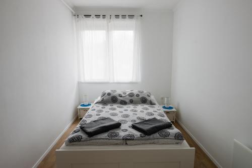 Cama en habitación con paredes blancas y ventana en Good Life Home Apartment Szentendre en Szentendre
