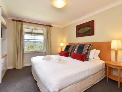 um quarto com uma grande cama branca e uma janela em Villa 2br Moscato Villa located within Cypress Lakes Resort em Pokolbin