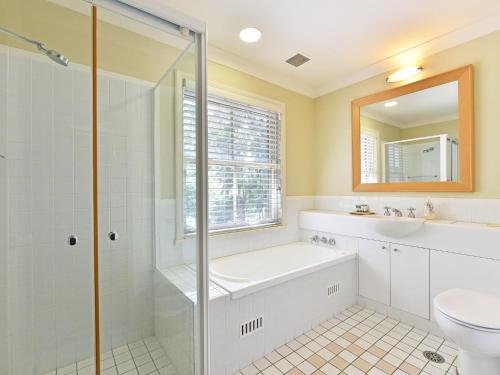 a bathroom with a tub and a sink and a toilet at Villa 2br Moscato Villa located within Cypress Lakes Resort in Pokolbin