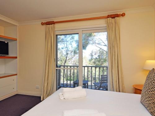 a bedroom with a bed and a balcony at Villa 2br Petit Verdot Villa located within Cypress Lakes Resort in Pokolbin