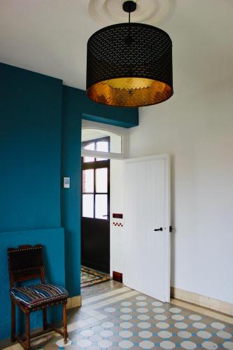 a room with a blue wall and a chair and a chandelier at Les Lilas in Sart-en-Fagne