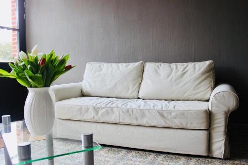 a white couch in a living room with a vase of flowers at Les Lilas in Sart-en-Fagne