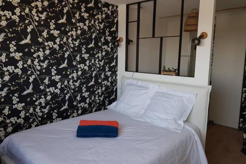 a white bed with a red and blue pillow on it at La Villa Thelma 5 étoiles, piscine, sauna et jacuzzi in Granville