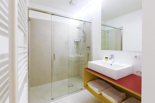 La salle de bains blanche est pourvue d'un lavabo et d'une douche. dans l'établissement Kleinkunsthotel, à Naturno