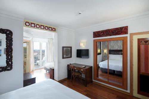 a bedroom with a bed and a desk with a mirror at Sercotel Hotel President in Figueres