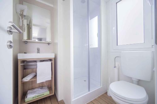 a white bathroom with a toilet and a shower at Villaggio Lido D'Abruzzo in Roseto degli Abruzzi
